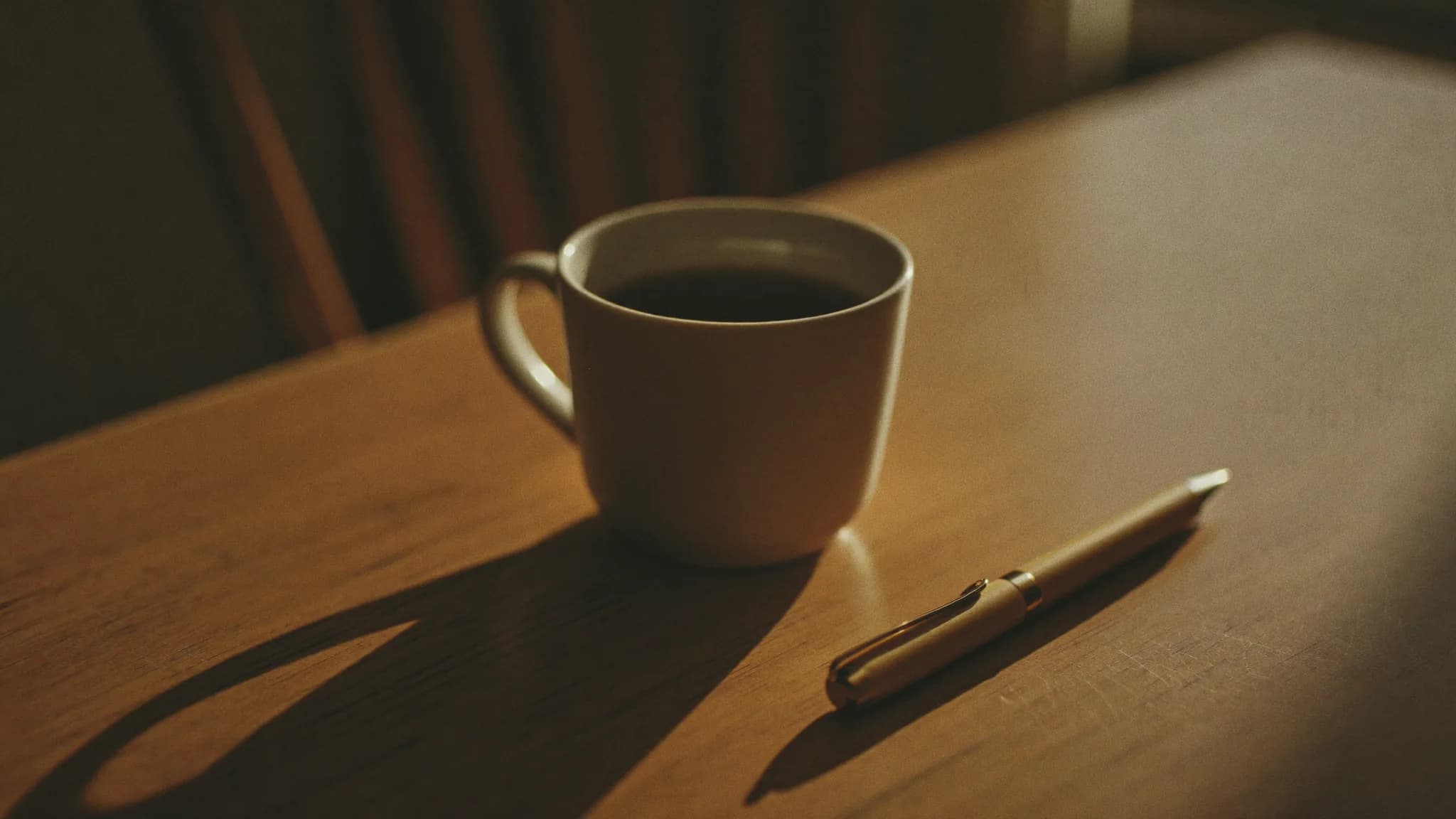 A coffee mug and a pen on a sunlit wooden table, the setting for working through a price objection.