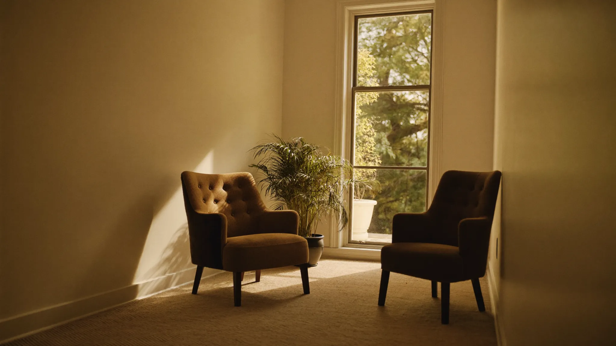 A bright, welcoming apartment leasing office with two chairs beside a large sunlit window.
