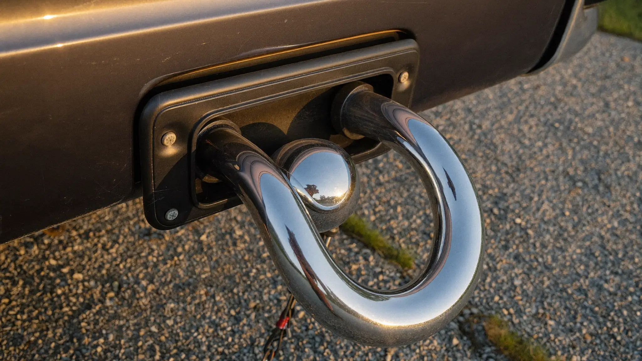 Close-up of a chrome tow hitch on the back of a work pickup truck in warm evening light